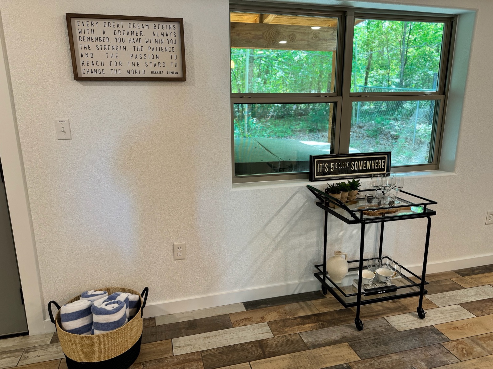 Bar cart with wine glasses inside the cabin, next to a sign reading It's 5 o'clock somewhere