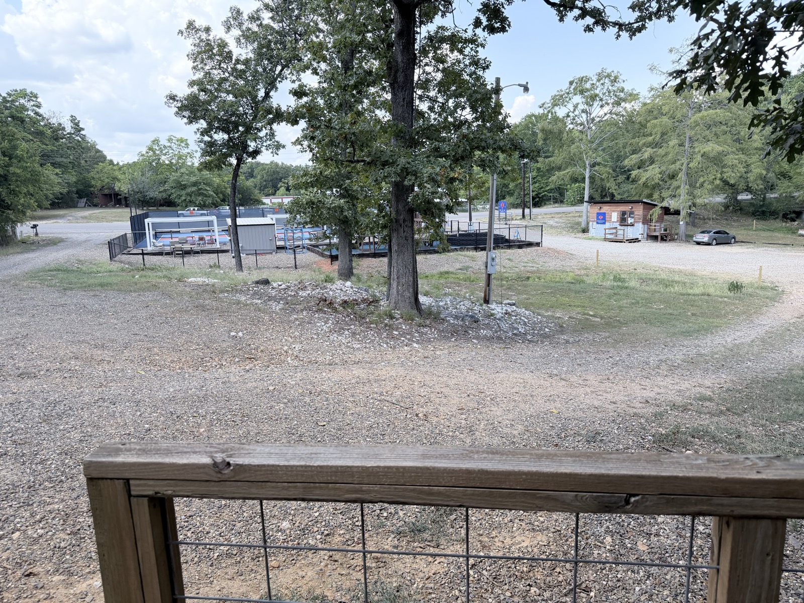 View from the cabin's covered porch railing straight across to Pickle Putt Pour's fenced pickleball court and bar building
