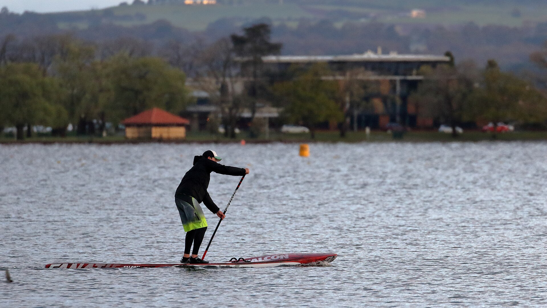 A paddleboarder standing on calm open water